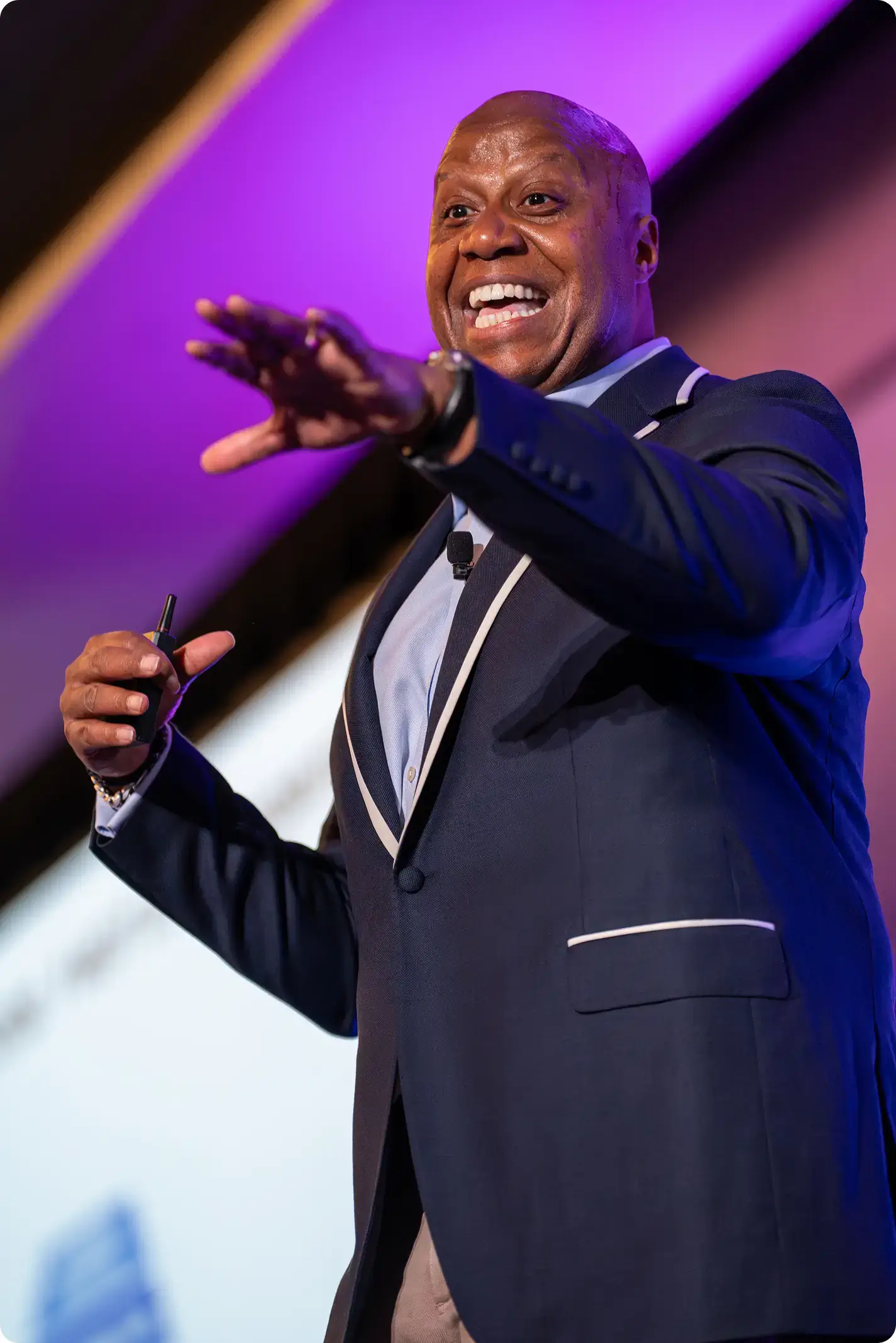 walter Walter Bond smiling and gesturing to the audience while holding a microphone on stage